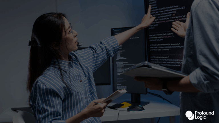 A developer pointing out code on a monitor to a colleague.