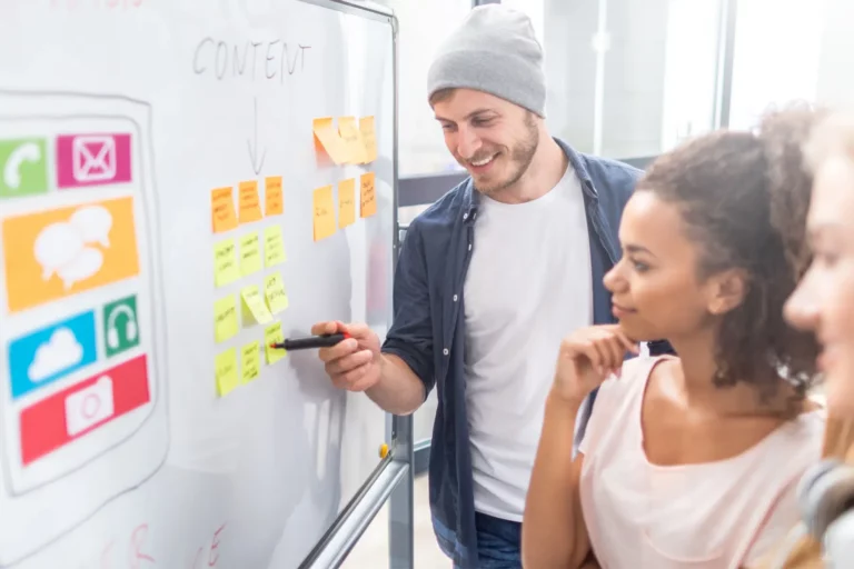 A team planning a mobile app with colorful notes on a whiteboard.