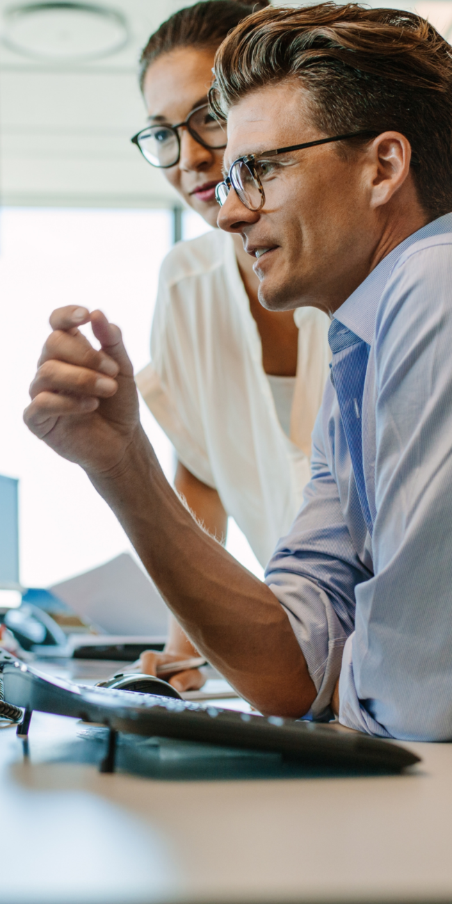 Man in business attire reviewing documents at computer while holding coffee, representing the first stage of a legacy journey.