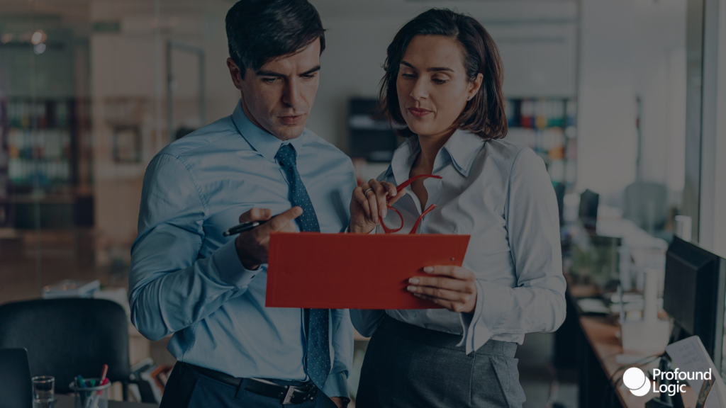 Two people looking at a red folder in an office
